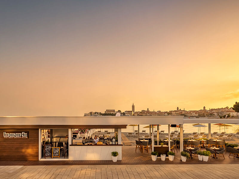 Elegantni beach club hotela Valamar Padova s pogledom na sončni zahod in staro mestno jedro Raba