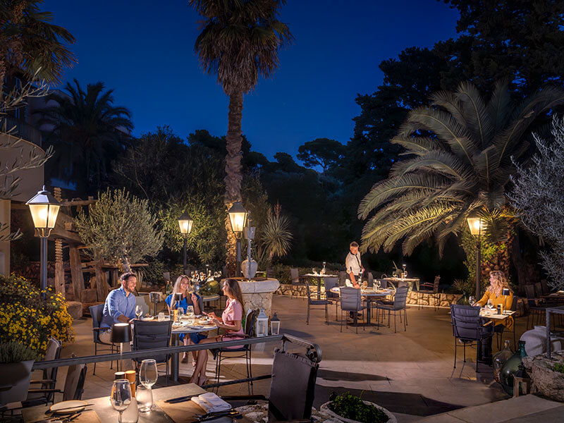 Elegantna terasa z gosti, ki večerjajo pod palmami v Restaurant & Wine Bar