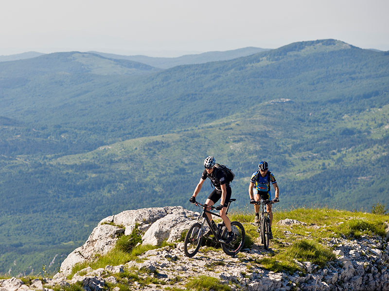Dwóch rowerzystów na górskim szlaku z panoramicznym widokiem