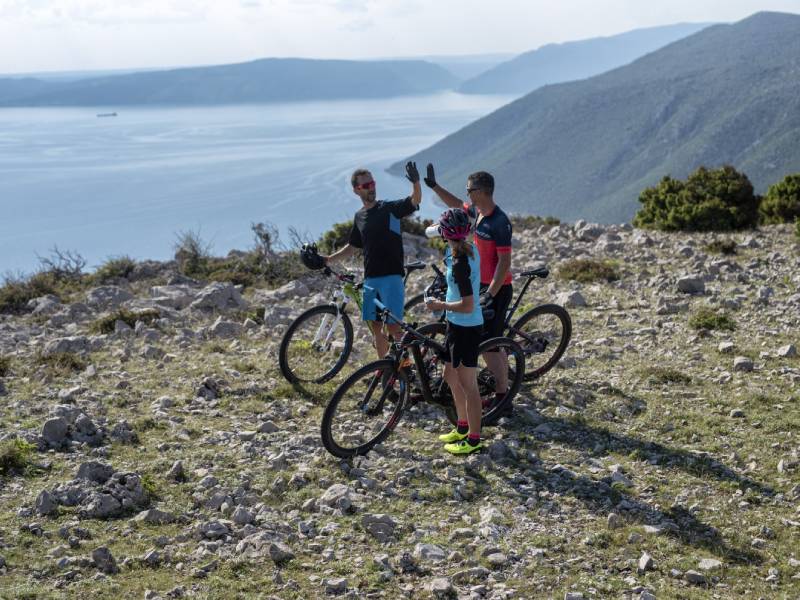 Grupa rowerzystów odpoczywa na malowniczym szczycie wzgórza