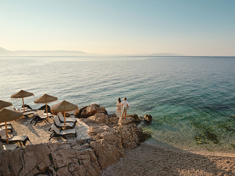 Peaceful beach scene at dusk in Rabac with deck chairs and parasols