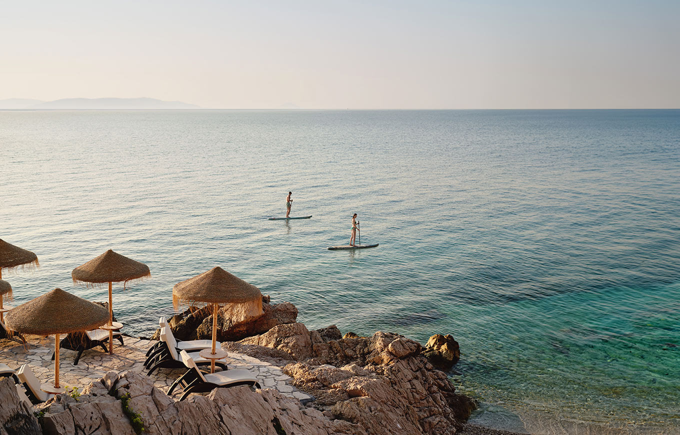 Paddleboarderi uživaju u mirnom moru blizu plaže u Rapcu