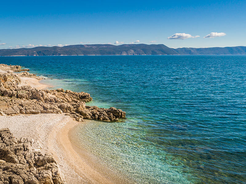 Natural coastal stretch with golden pebbles and blue water