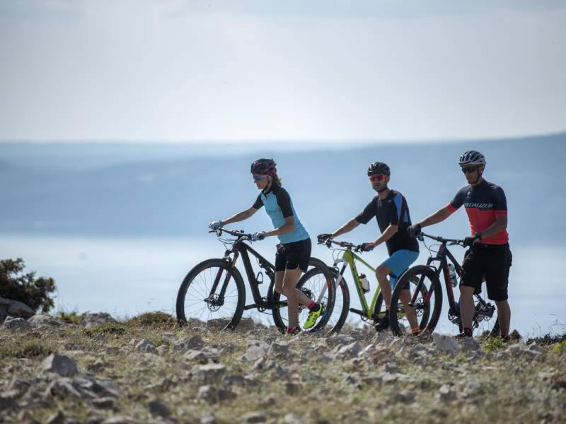 Grupa rowerzystów zatrzymuje się na nadmorskiej trasie z widokiem na Kvarner