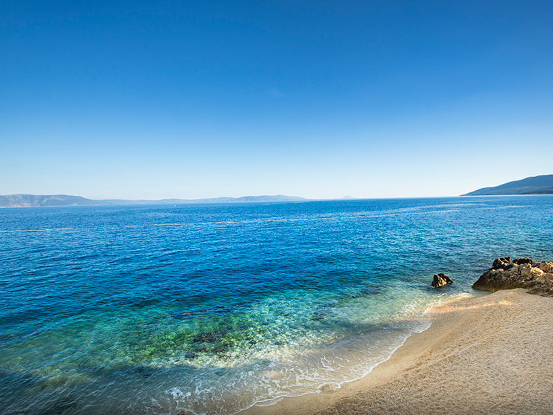 Vibrant blue sea and rocky beach at Lanterna in Rabac