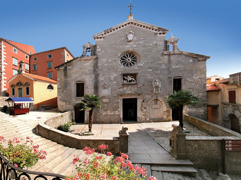 Stone church with bell tower and floral courtyard