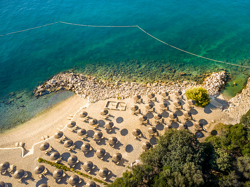 Vue aérienne de la plage de galets Val Riviera Relax Beach avec des transats et des parasols.