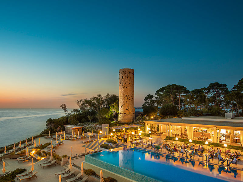 Aerial view of Miramare Restaurant at Isabella Valamar Collection Island Resort illuminated at night.