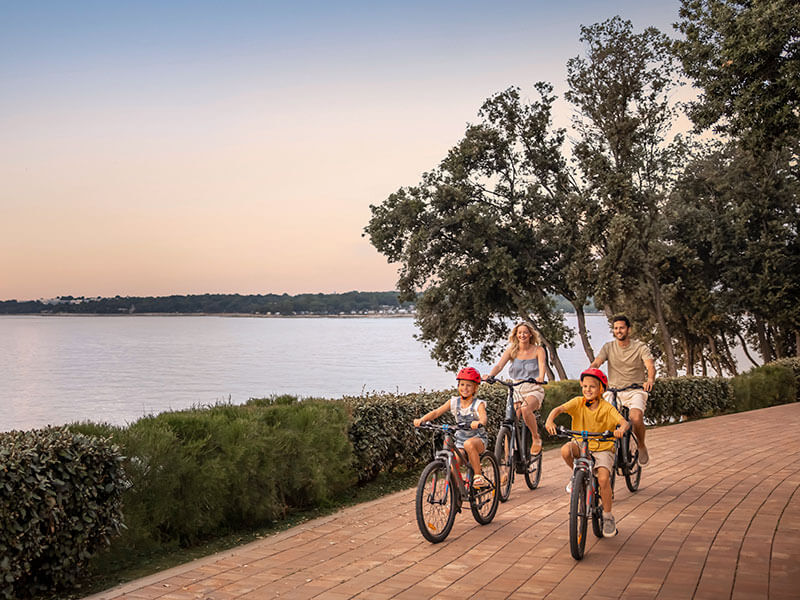 Family cycling along the Adriatic coast at sunset