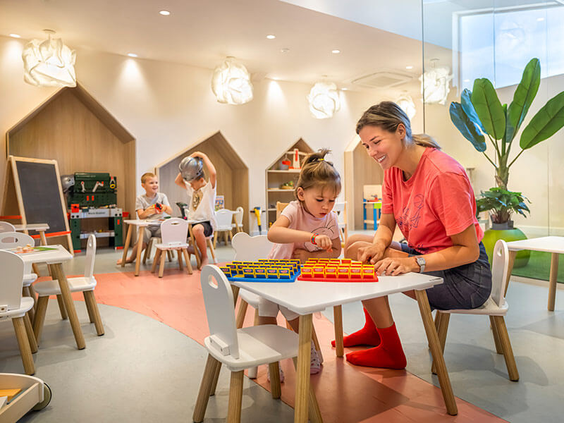 Ein kleiner Junge und ein Mädchen sitzen in Sitzsäcken und spielen Spiele auf PlayStations in der Game Lounge des Girandella Valamar Collection Resort