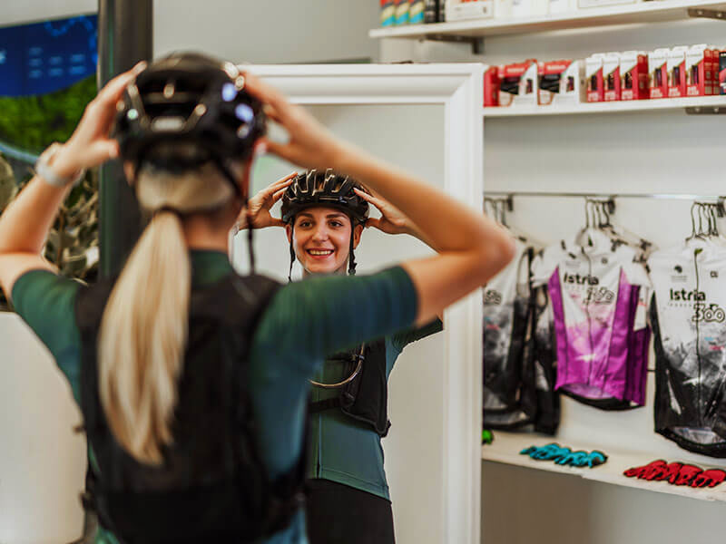 Woman preparing for a ride by fitting her helmet at a bike rental