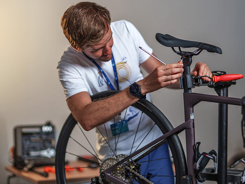 Bike mechanic fine-tuning a bicycle at a repair station