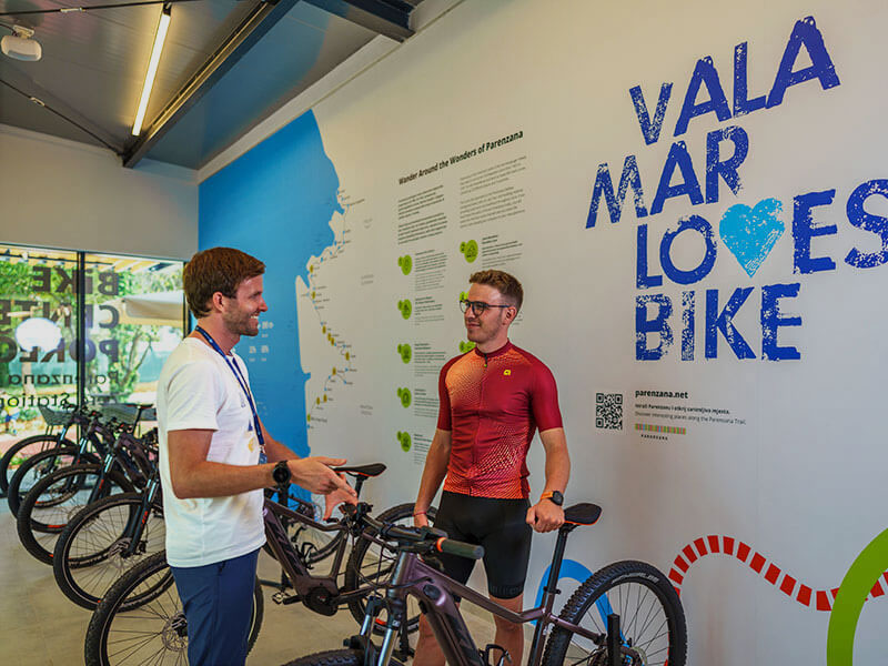 Man discussing cycling routes with a Valamar guide at a bike center promoting the Parenzana Trail in Croatia