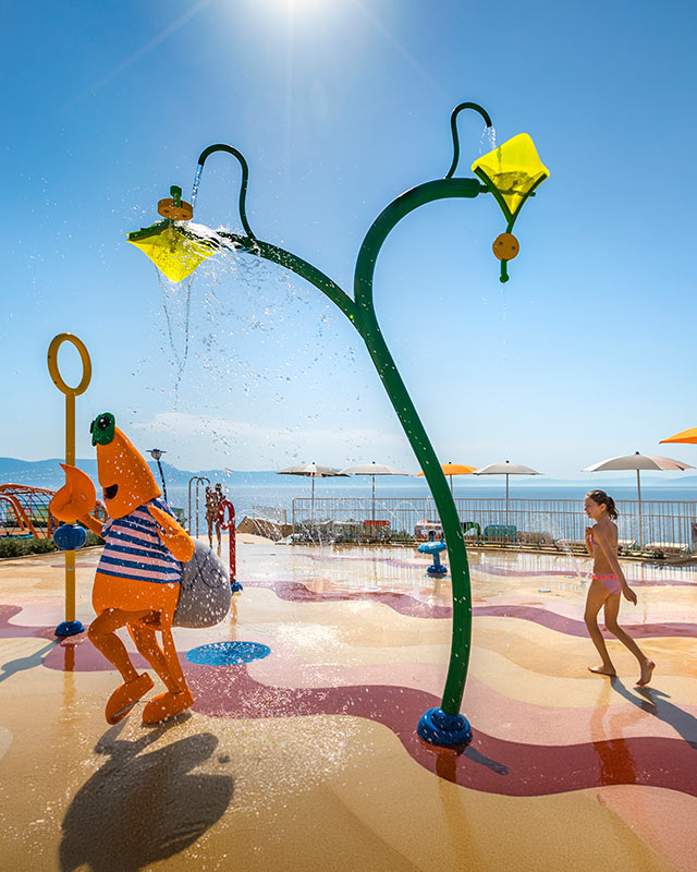 Maro der Krabbe, das Maskottchen von Valamar, rennt mit Kindern auf dem Wasserspielplatz.