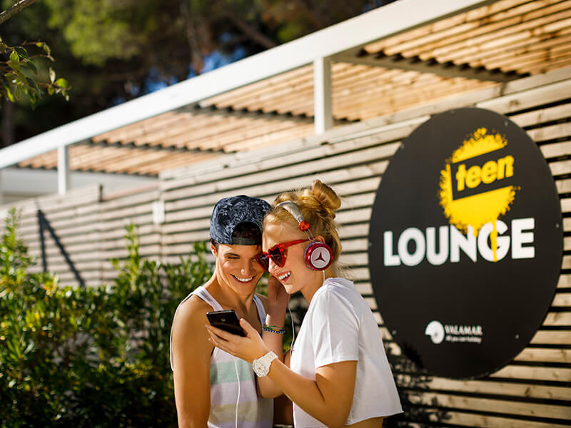 Two teens listening to music outside the Teen Lounge