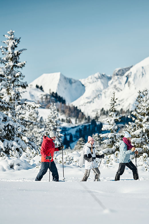 Three individuals enjoy cross-country snowshoeing through the snowy landscape of Obertauern