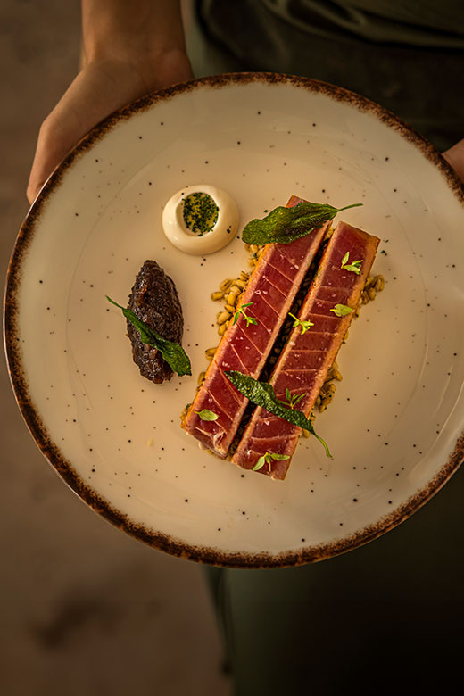 A plate with a piece of tuna accompanied by an assortment of fresh vegetables.