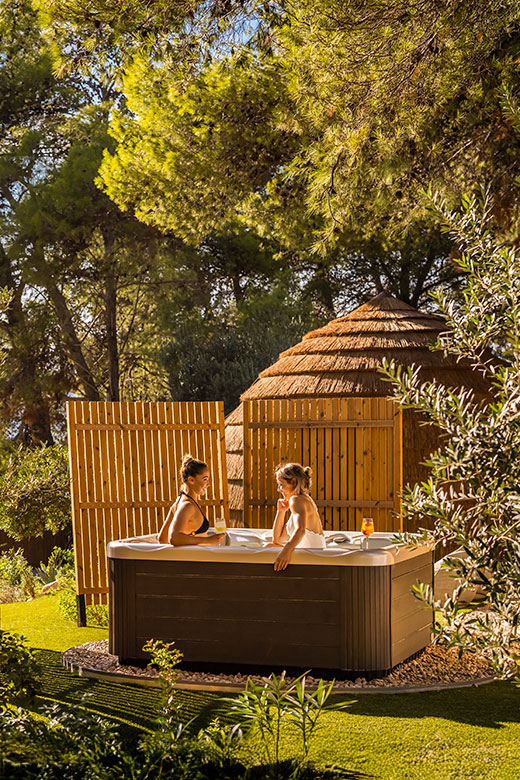 Two women relaxing in the outdoor jacuzzi at [PLACES] Hvar by Valamar