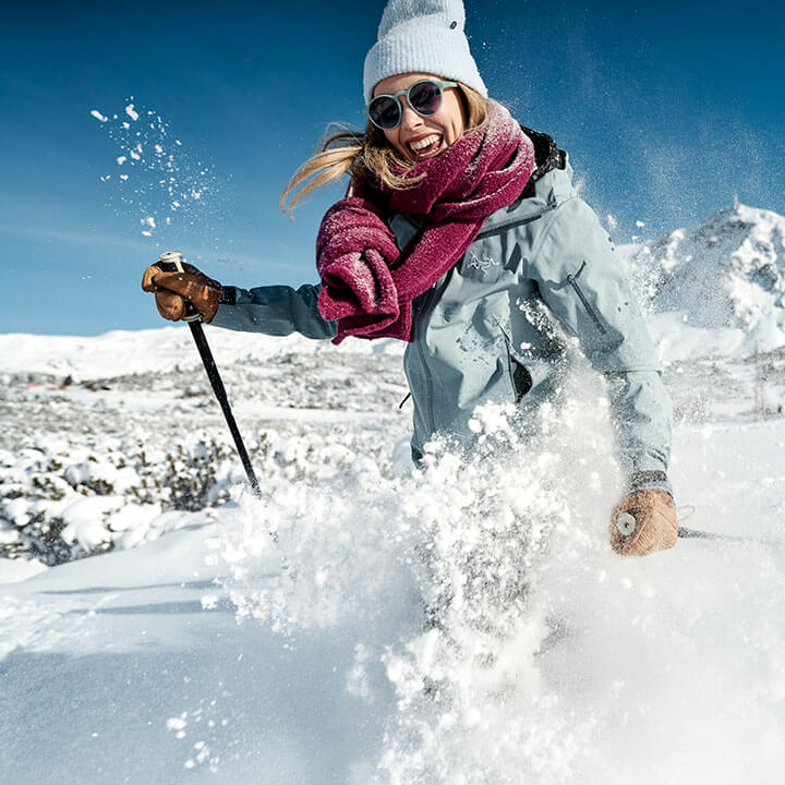 Happy woman dressed in winter gear skiing on snowy slopes in Austria