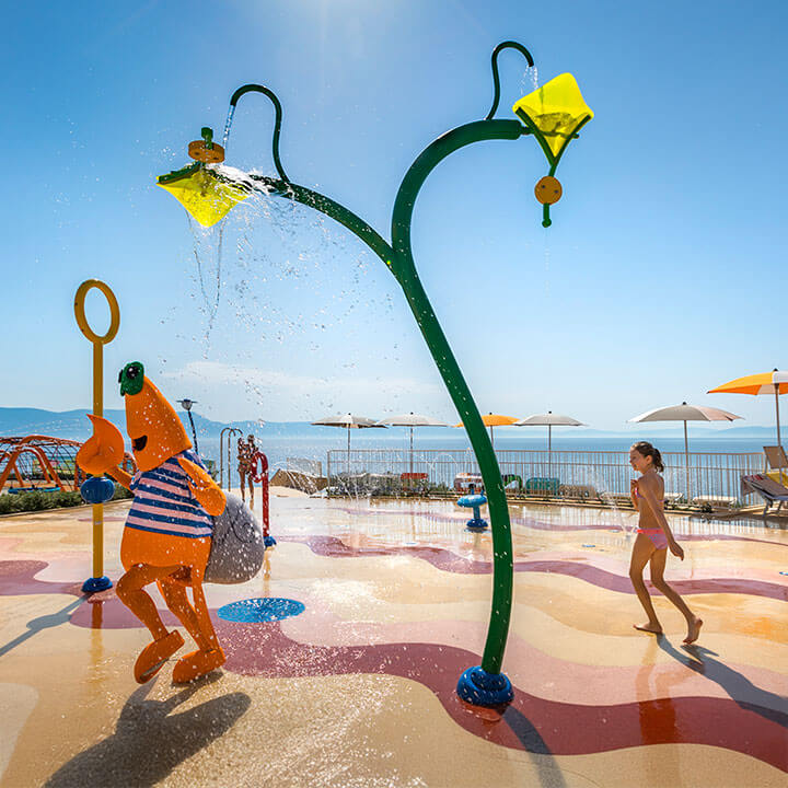 Maro der Krabbe, das Maskottchen von Valamar, rennt mit Kindern auf dem Wasserspielplatz.