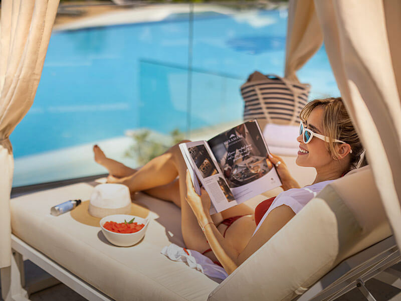 Woman reading a magazine by the pool at Valamar Lacroma Hotel in Dubrovnik