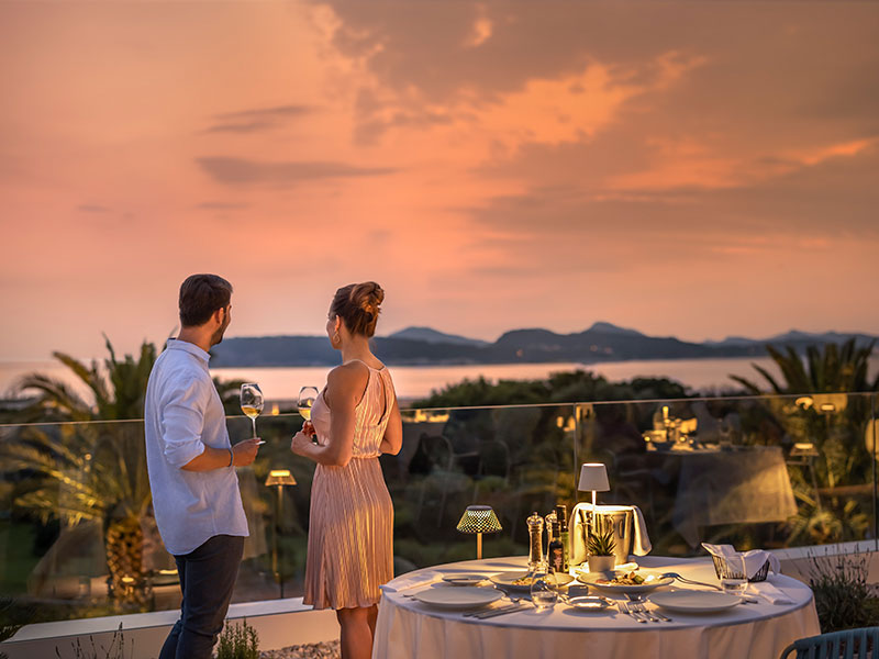 A couple drinking wine on a luxurious terrace at sunset