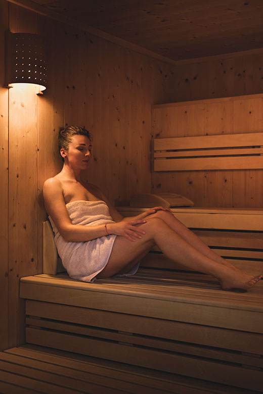 Woman relaxing in a wooden sauna wrapped in a towel