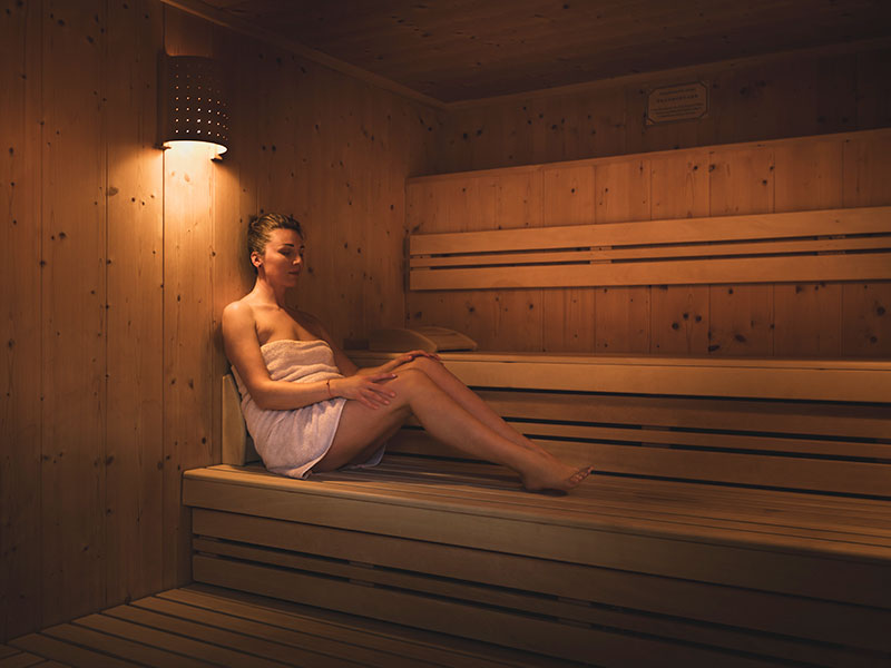 Ospite della spa che si gode una calda sauna rivestita in legno.