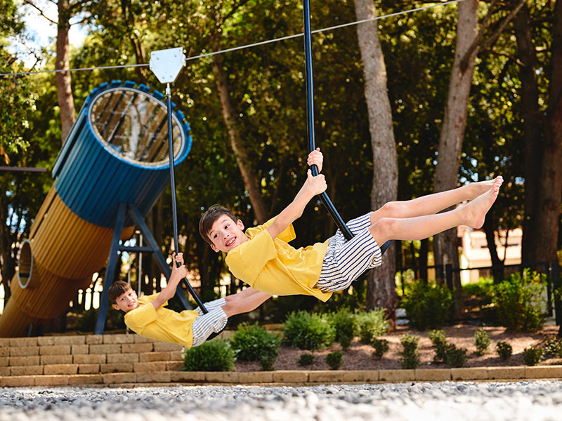 Kinder auf Schaukeln auf dem Außenspielplatz des Pical Family Hotels in Istrien